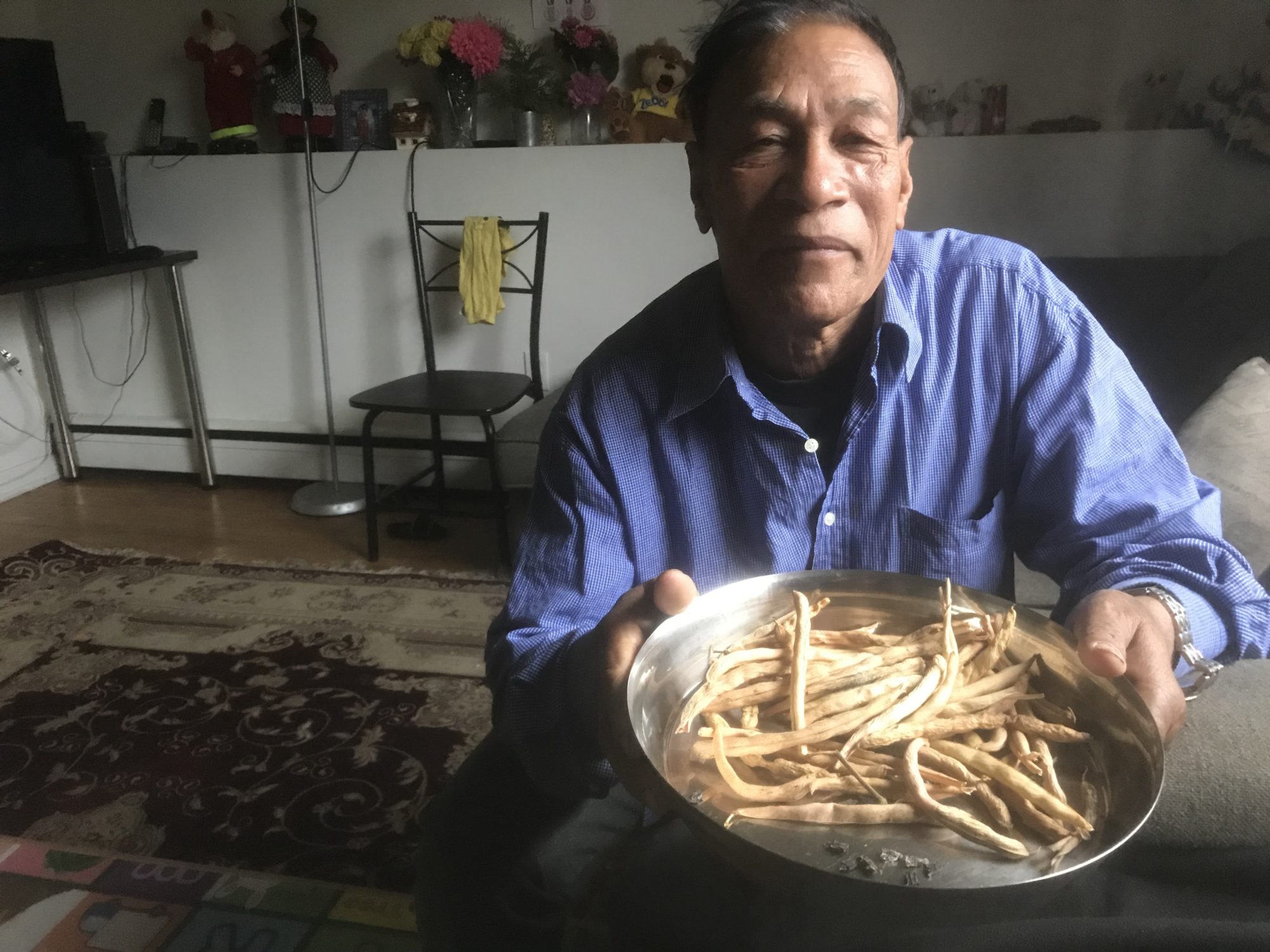 Chandra Bahadur Pradhan holds a bowl with crop from the community garden